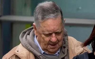 William Lloyd-Lavery entering court, it is a shot of him from the shoulders up. He has grey hair and is wearing a tan jacket over a grey hoodie and blue and white striped shirt. He is looking down towards the ground.
