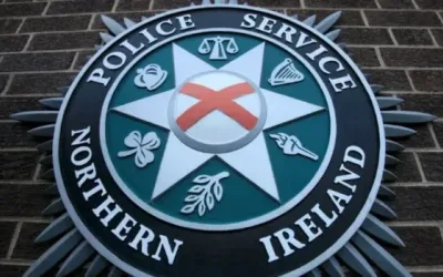 A close up of the Police Service of Northern Ireland crest against a brown brick wall