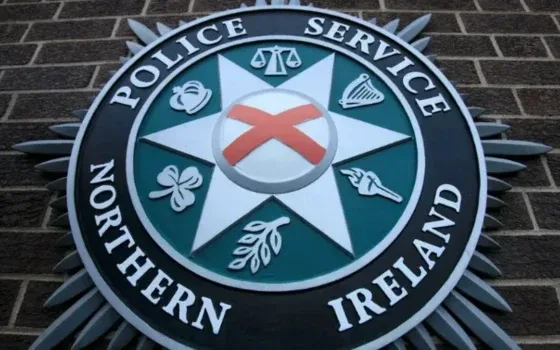 A close up of the Police Service of Northern Ireland crest against a brown brick wall